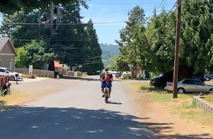 Man biking down a road with no sidewalks