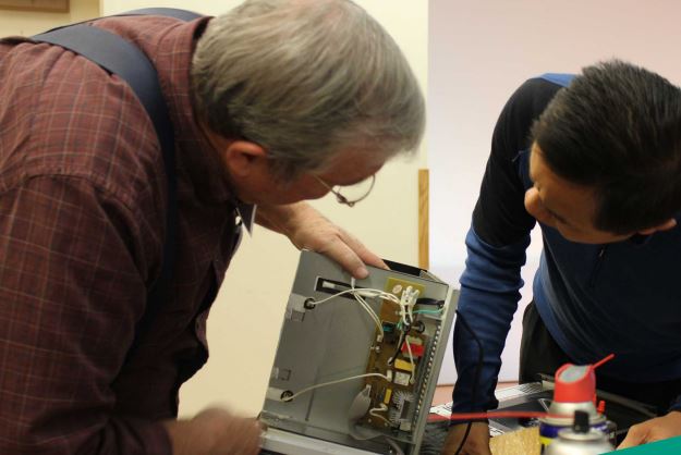 man with white hair fixing electronics