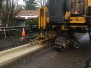 New curb and gutter being installed on 22nd Ave with a curb machine.