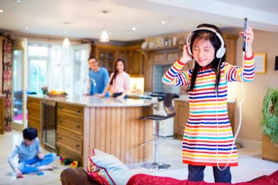 photo of child wearing headphones with family in the background
